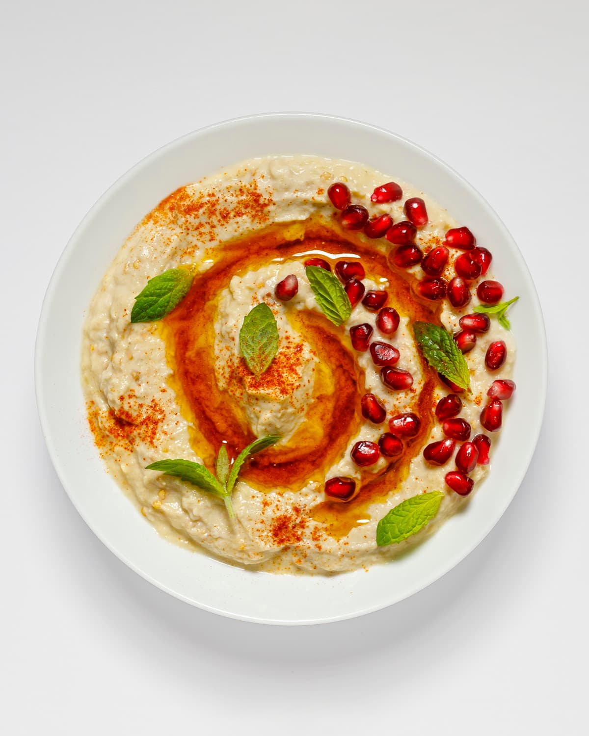 Bowl of Smart Gourmet Baba Ghanouj with pomegranate seeds, mint and paprika