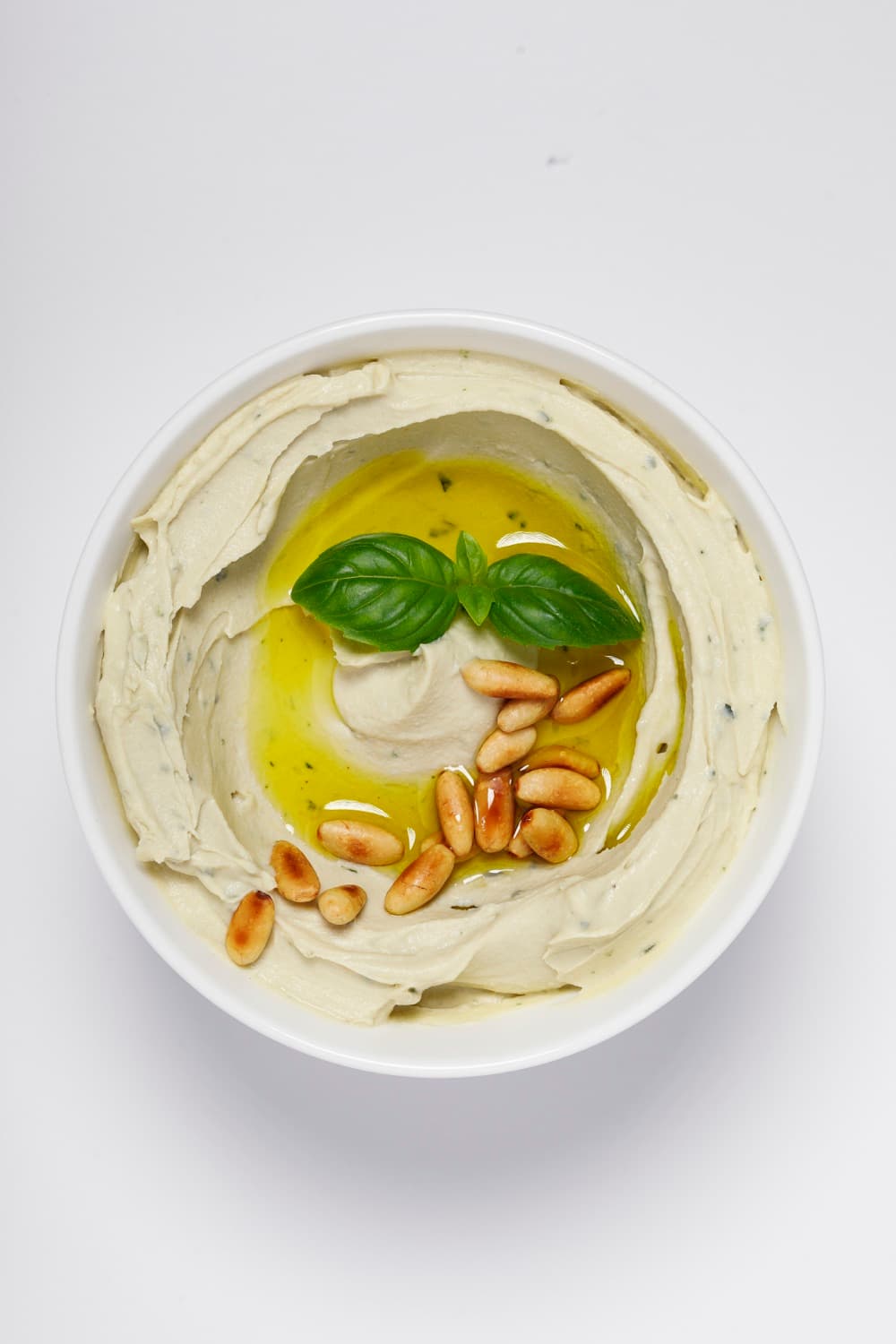 Bowl of Smart Gourmet Basil Hummus with fresh basil and pine nuts