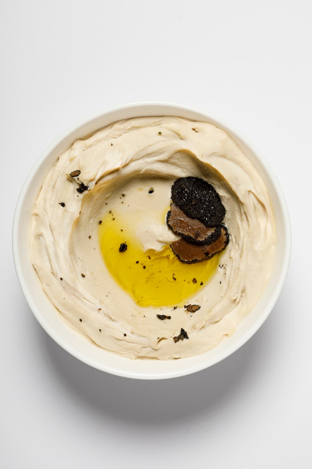 Bowl of Smart Gourmet Truffle Hummus topped with sliced black truffle
